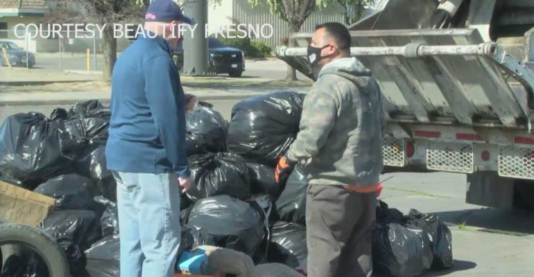 Two men loading trash into trash truck